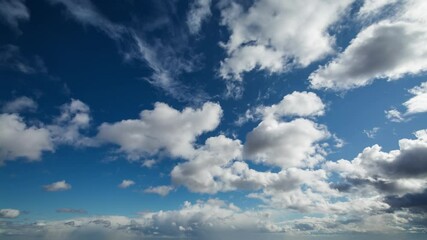 Wall Mural - White fluffy clouds moving softly across the sky in beautiful timelapse. Clear blue sky is being gradually covered with clouds in bright sunshine, some stormy clouds appearing in the end.