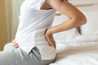 © Nutlegal - Pregnant woman touching tummy and suffering from back ache sitting on bed at home. Young attractive pregnant mother get back pain, her fetus or baby and belly bigger than before that mom get painful