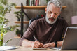 © InsideCreativeHouse - Middle aged businessman in casual clothes making notes in notepad while sitting in his office