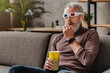 Senior man watching 3d movie at home with popcorn