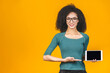 Smiling afro american young student woman showing blank tablet computer isolated over yellow background.