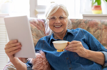 Wall Mural - Senior woman using digital tablet at home
