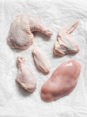 Pieces of raw butchered chicken - legs, thighs, breast, wing on a light background, top view