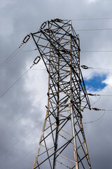 High voltage steel power grid pylon on a cloudy day.