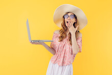 Shocked Surprised A Beautiful Woman In A Straw Hat And Sunglasses Uses A Laptop On A Yellow Background