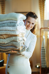 Wall Mural - smiling elegant woman looking out from huge pile of sweaters