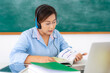 © ake1150 - Asian woman teacher reading a-loud book to student via video conference e-learning in laptop with blackboard at classroom. Homeschooling and distance learning ,online ,education and internet.
