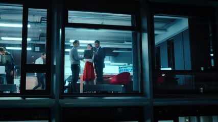 Poster - Footage from Outside the Window: Daily Meeting in the Office. Senior Manager Explaining New Business Strategy to Young Financial Specialists on a Laptop Computer while Standing Next to a Window.