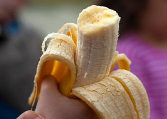 Half-peeled banana in the hand of a child