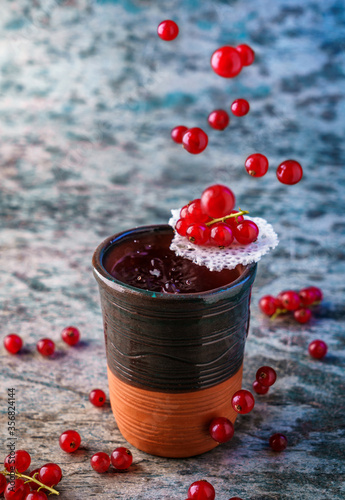 Fresh berry alcoholic cocktail with vodka, ice, currant in ceramic glass on textured background. Studio shot of drink in freeze motion, flying drops and berries. Summer cold drink and cocktail