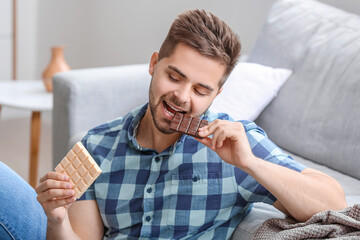 Wall Mural - Handsome young man with tasty chocolate at home