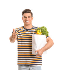 Wall Mural - Young man with food in bag showing thumb-up gesture on white background