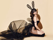 © Dmitry Lobanov - Sensual woman in black high boots, sexy transparent cloth and lace rabbit ears mask sits on her knees side to us