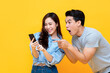 © Atstock Productions - Amazed attractive young Asian couple looking at smartphone together isolated on yellow studio background