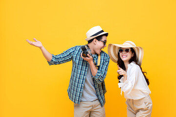 Wall Mural - Excited smiling lovely Asian couple tourists in summer casual clothes isolated on colorful yellow background