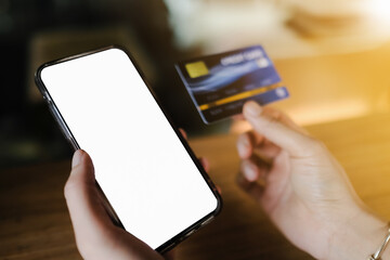 Wall Mural - Mockup image of hand’s woman holding black mobile phone and credit card with blank screen in cafe.