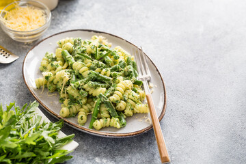 Wall Mural - pasta with green vegetables and creamy sauce. fusilli pasta with asparagus beans and spinach on grey stone background