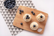 Homemade cupcakes with blueberry and vanilla cream on wooden board. Flat lay style. Copy space.