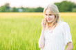 © PKpix - Beautiful young woman speaking on mobile phone against green meadow countryside summer background.