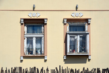 Two windows with ornaments above on light yellow wall