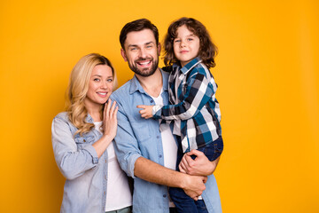 Photo wife beautiful mother lady handsome husband dad guy couple hug hold carry little preteen son boy happy family wear casual shirts clothes isolated yellow color background