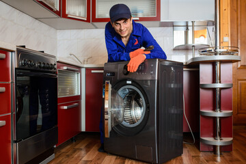 Young smiling happy man plumber handyman in blue overalls