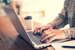 © methaphum - businessman freelance sitting using working on his computer notebook laptop send work with cup coffee on the table wooden in cafe. Social Distancing. filter tone vintage style.