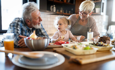 Wall Mural - Happy grandparents with grandchildren making breakfast in kitchen