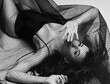 © Dmitry Lobanov - Young beautiful brunette woman in black bodysuit lingerie and high boots sexy lying on floor under veil fata. Top view