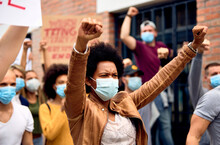 African American Woman Wearing Protective Face Mask While Protesting With Arms Raised On City Streets.
