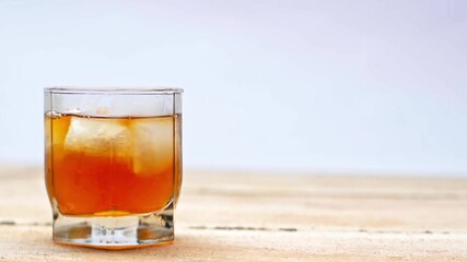 Wall Mural - glass of whiskey with ices cubes on wooden table isolated on white