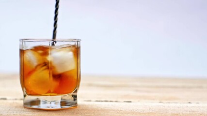 Wall Mural - mixing of whiskey and ice cubes in glass with cocktail spoon isolated on white