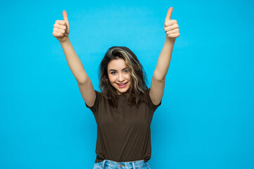 Wall Mural - Portrait of beautiful woman with thumbs up on blue background