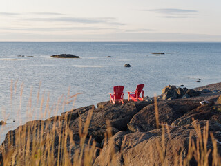 Two red chairs on a rocky coastine at sunrise in Petit-Rocher, New-Brunswick