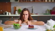 © stockbusters - Woman choosing salad instead cake on kitchen. Girl with fork trying fresh salad