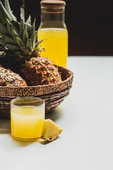 Canvas Print - selective focus of fresh pineapple juice in glass and bottle near delicious fruit in basket on white background isolated on black