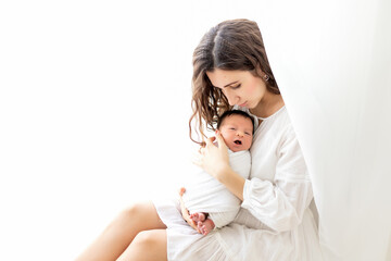 mom holding with newborn baby sitting by the window, mom with son, place for text. Mother's day