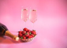 Fresh Strawberry, Bottle Of Champagne And Glasses Of Champagne On Pink Background. Selective Focus.