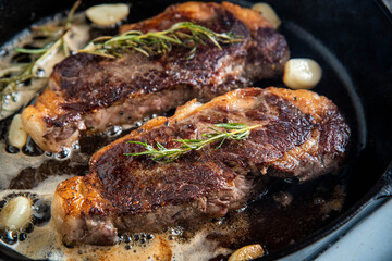 cooking new york strip steak on skillet pan