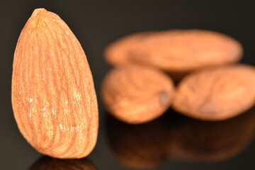 Roasted flavored almonds, close-up, on a black  background.