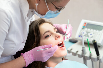 Doctor examining patient mouth with instrument, mirror tool and modern equipment. 