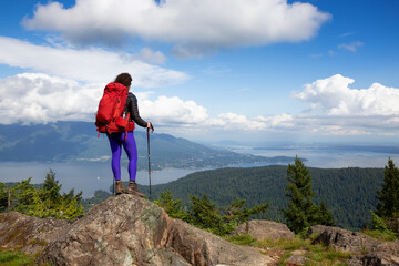 Wall Mural - Adventurous Girl hiking with a backpack on top of a mountain with a beautiful Canadian Nature Background. Taken in Bowen Island, near Vancouver, British Columbia, Canada.