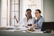 © Maskot - Female architects discussing while working at table in home office