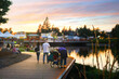 Dried fern stalks are in focus as the sun sets behind a festival as families enjoy the early evening along the River in Spokane, Washington.  