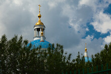 Blue Domes Of An Orthodox Church With Golden Crosses Surrounded By Tall Trees With Lush Foliage