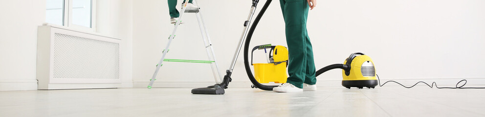 Poster - Professional young janitor using vacuum cleaner indoors, closeup view. Banner design