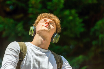 young red-haired man with headphones listening to music the eyes closed