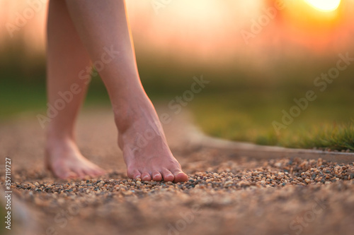 Fotografía barefoot girl walking on the walkway ground stone with sunset light shine