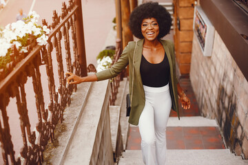 Wall Mural - Fashionable girl in a summer city. Black lady in a green jacket