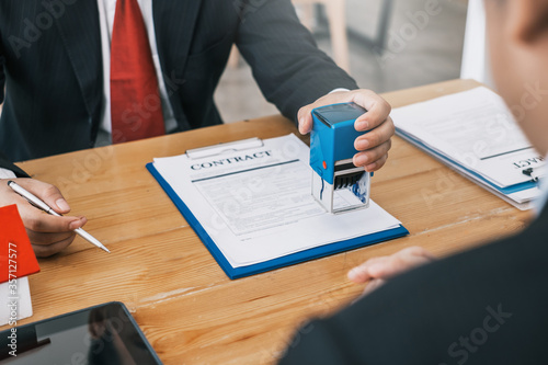 Fotografía Businessman stamping with approved stamp on document at meeting.
